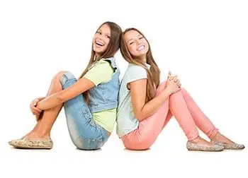 2 teenage girls sitting back to back